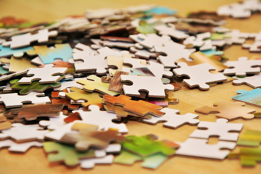 Scattered Jigsaw Puzzle Pieces on Wooden Table