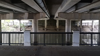 Concrete bridge underside with pillars and river view