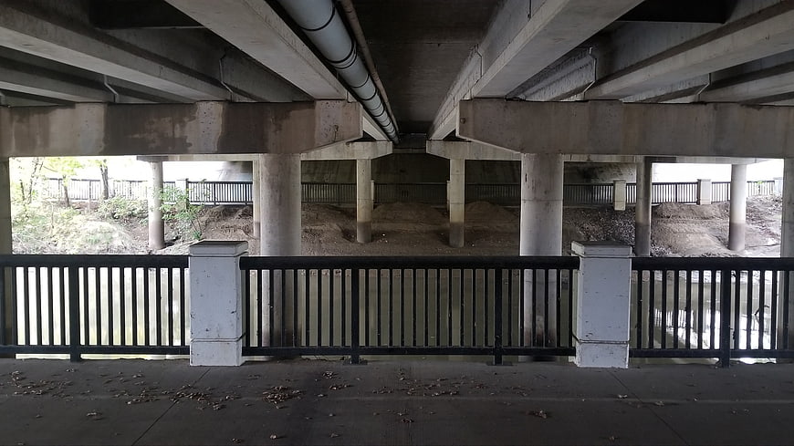 Concrete bridge underside with pillars and river view