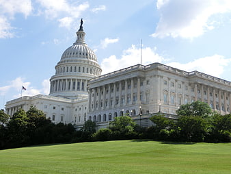 United States Capitol Building Exterior With Green Lawn And Blue Sky