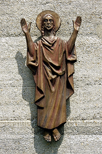 Bronze Statue of Jesus Christ with Raised Hands on Stone Wall