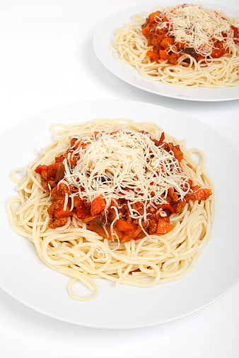 Two plates of spaghetti bolognese with parmesan cheese