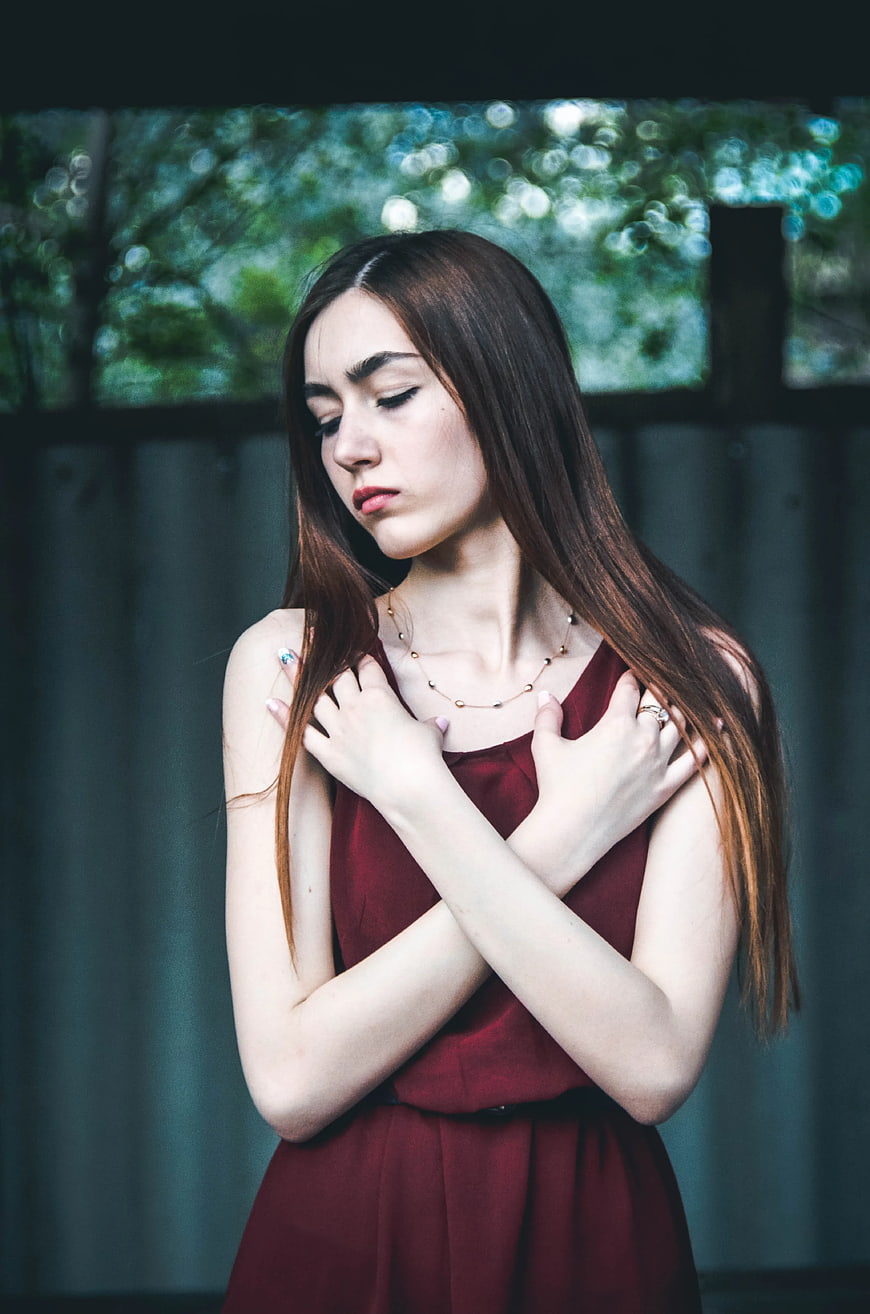 Pensive Woman in Maroon Dress with Hands on Chest