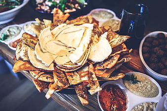 Assorted pita chips and dips on wooden table