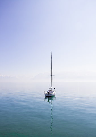 Minimalist Sailboat on Calm Blue Water with Mountain Reflection