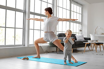 Mother doing yoga with toddler in bright living room