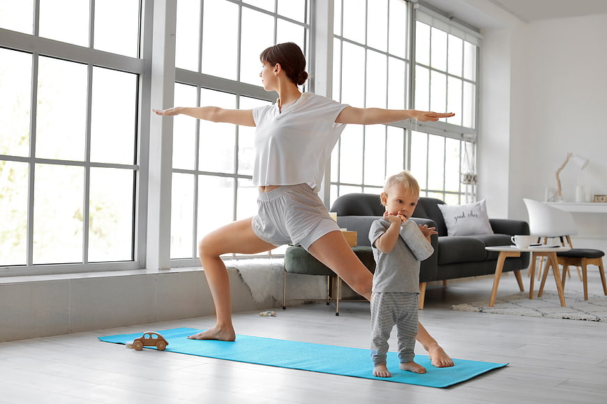 Mother doing yoga with toddler in bright living room