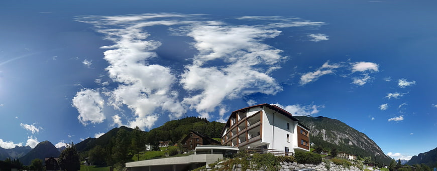 Panoramic View of Alpine Chalet and Mountains Under Blue Sky
