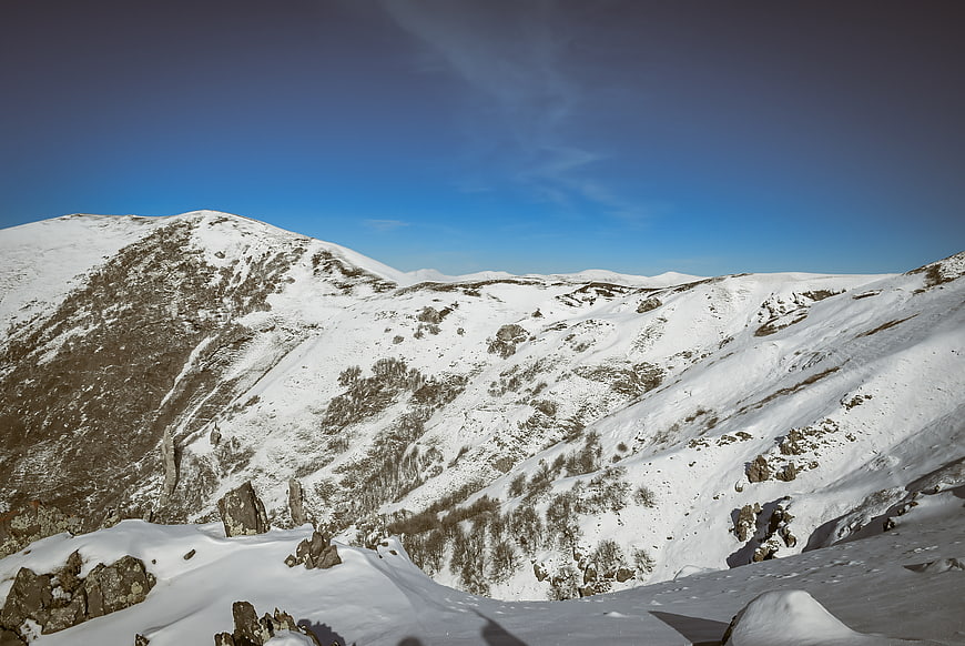 Snow-covered mountain landscape with rocky slopes and blue sky