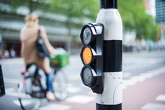 Close-up of amber traffic light with blurred cyclist in background