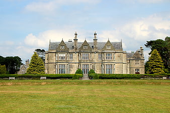 Historic Stone Manor House With Manicured Gardens And Blue Sky