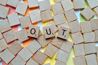 Scrabble tiles spelling OUT on rainbow background