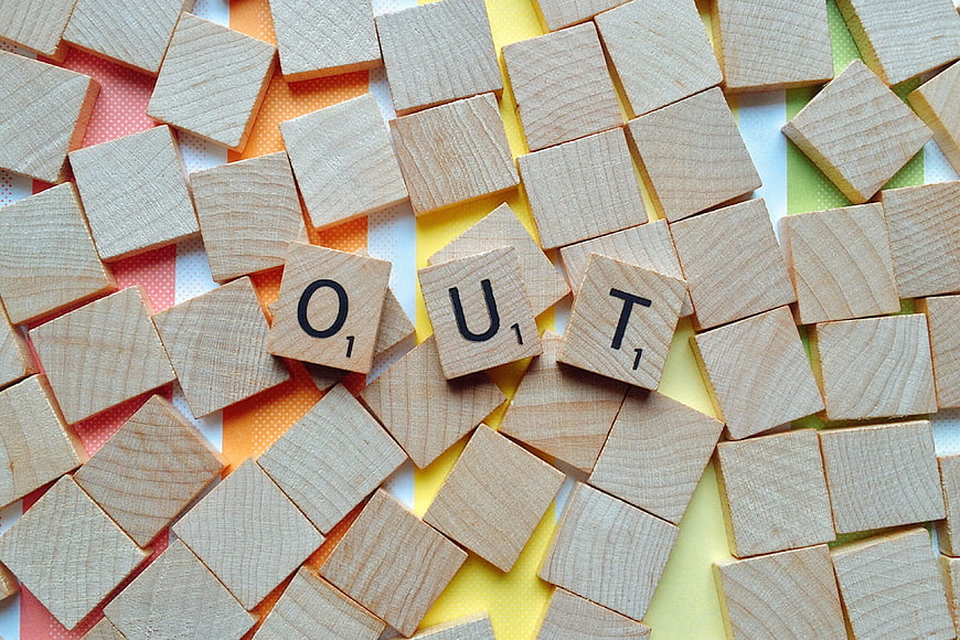 Scrabble tiles spelling OUT on rainbow background