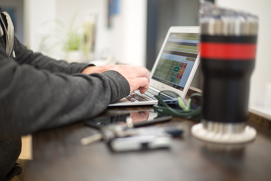 Man Typing on Laptop at Desk with Coffee Mug