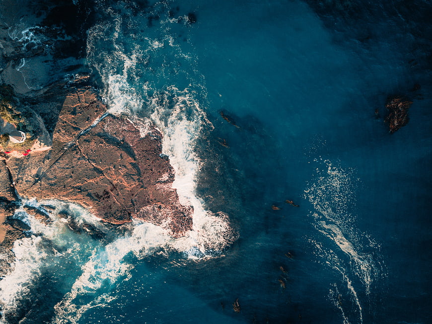 Aerial View of Rocky Coastline with Blue Ocean Waves