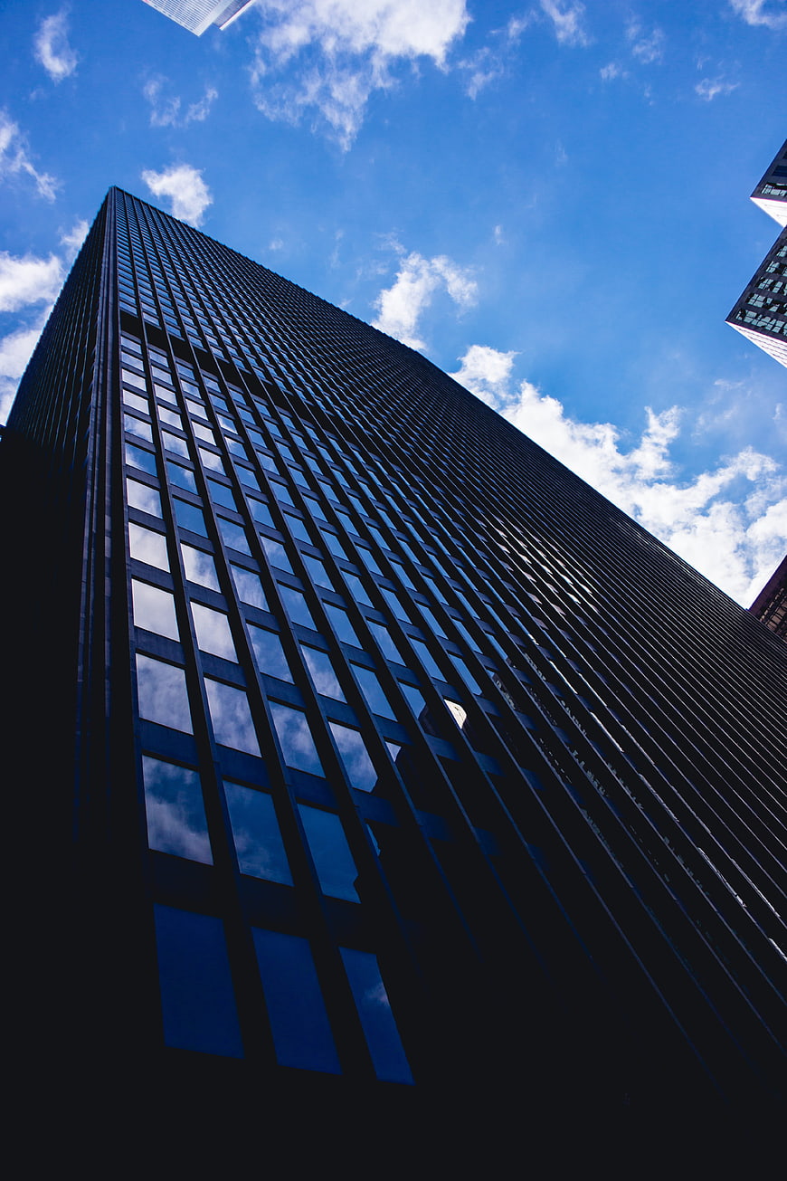 Low angle view of modern glass skyscraper against blue sky