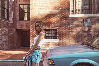 Stylish Young Woman Leaning on Vintage Car in Urban Setting
