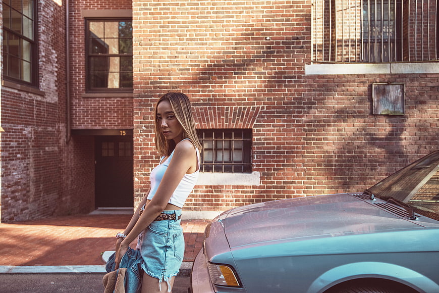 Stylish Young Woman Leaning on Vintage Car in Urban Setting