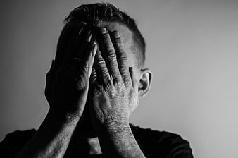 Black and white portrait of man holding head in hands
