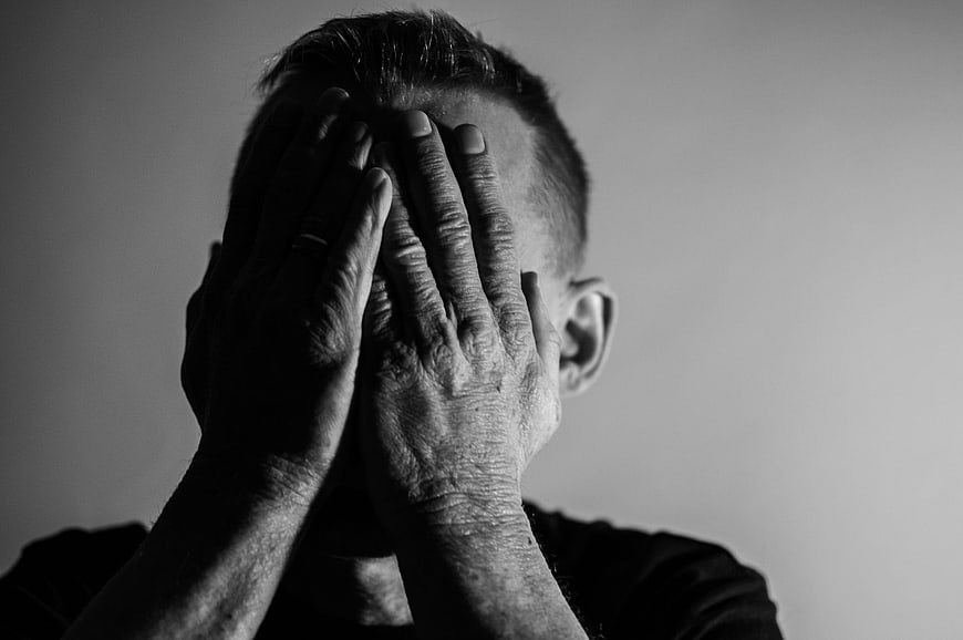 Black and white portrait of man holding head in hands