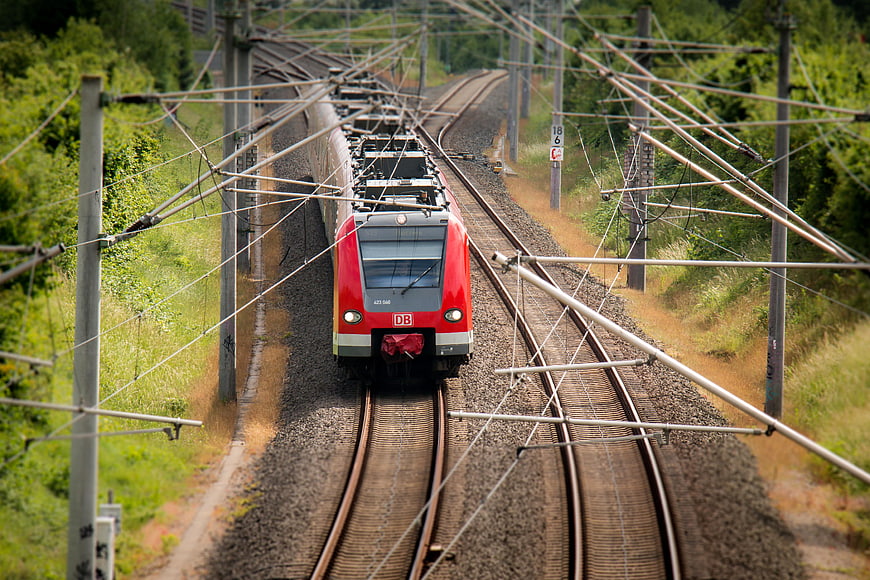 Red DB Train on Curved Railway Tracks in Green Landscape