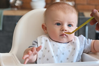 Baby Eating in High Chair with Spoon