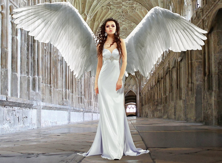 Woman with large white angel wings in gothic cathedral