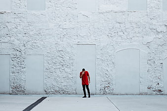 Man in Red Shirt Standing Against White Brick Wall