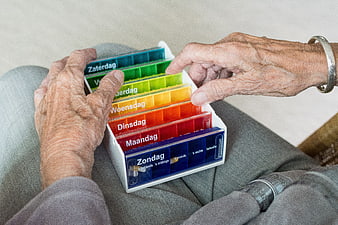 Elderly Woman Organizing Colorful Weekly Pillbox