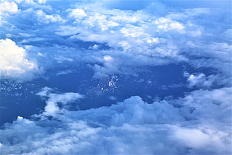 Aerial View of Snow-Capped Mountains Through Clouds