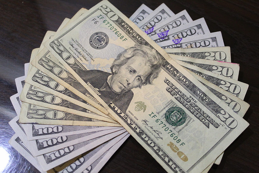 Fanned US Dollar Bills On Dark Wooden Table