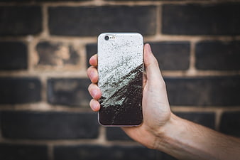 Hand holding smartphone with black and white speckled case