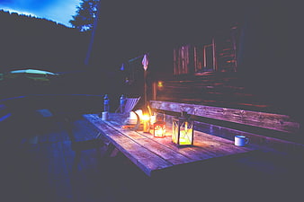 Rustic wooden cabin deck with lanterns at night