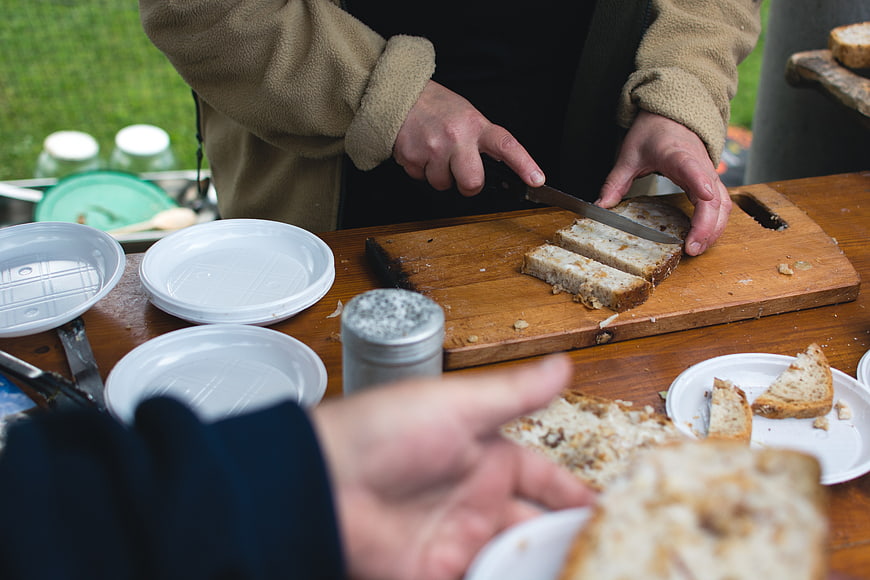 Hands slicing traditional Czech bread on wooden board