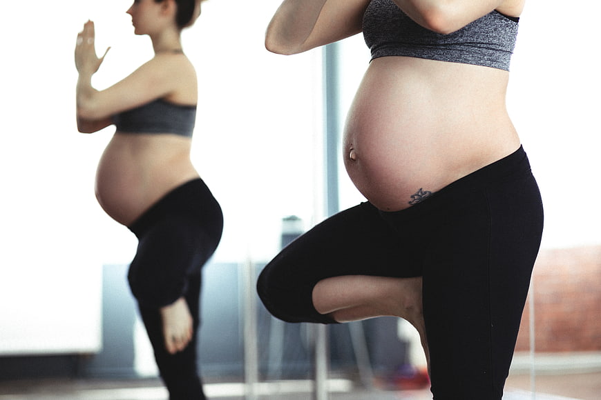 Pregnant woman doing yoga in front of a mirror