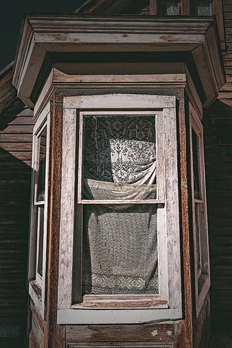Vintage wooden bay window with lace curtains on old house
