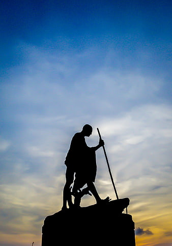 Silhouette of Mahatma Gandhi Statue Against Sunset Sky