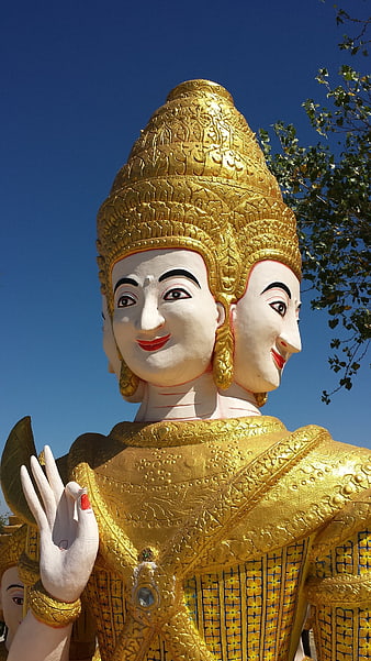 Golden Four-Faced Brahma Statue Against Blue Sky