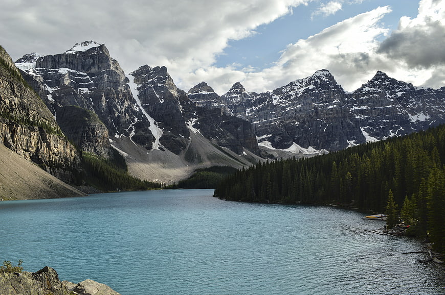Turquoise mountain lake surrounded by pine forest and snow-capped peaks