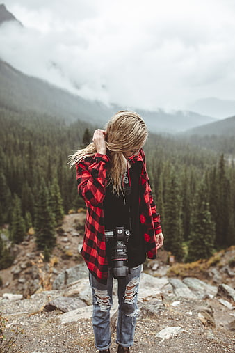 Female photographer with camera in red flannel shirt on mountain trail