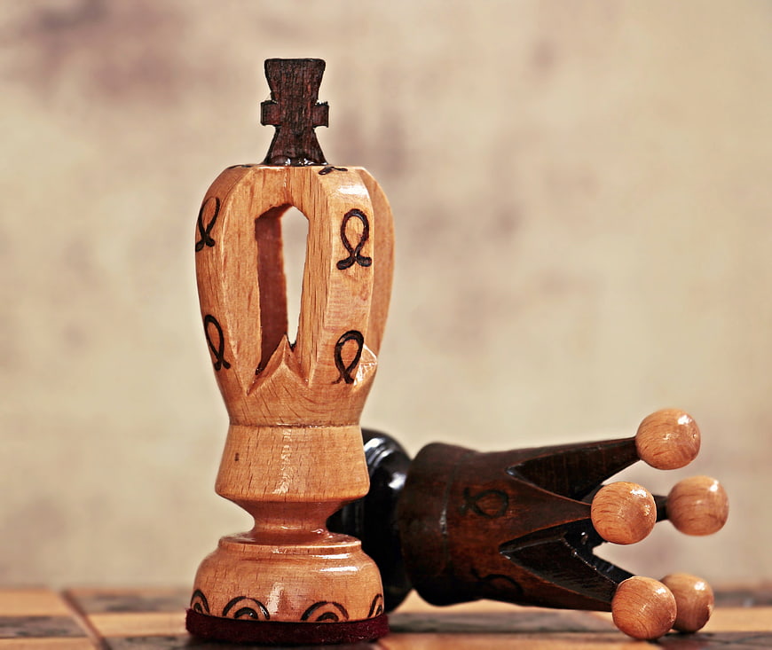 Wooden Chess Queen Standing Over Fallen King Piece