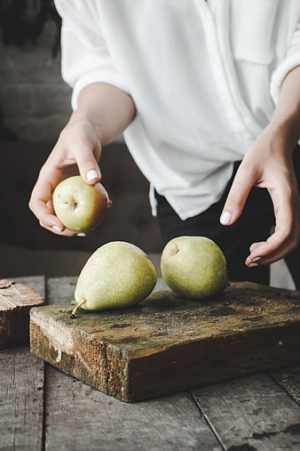Woman holding fresh pears on rustic wooden board