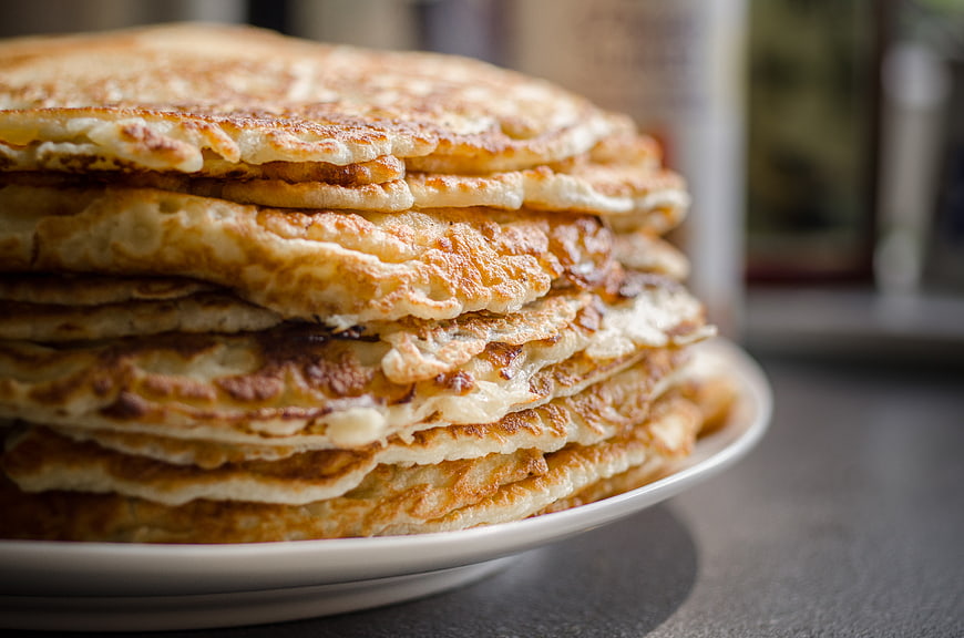 Close-up of golden stack of fluffy pancakes on white plate