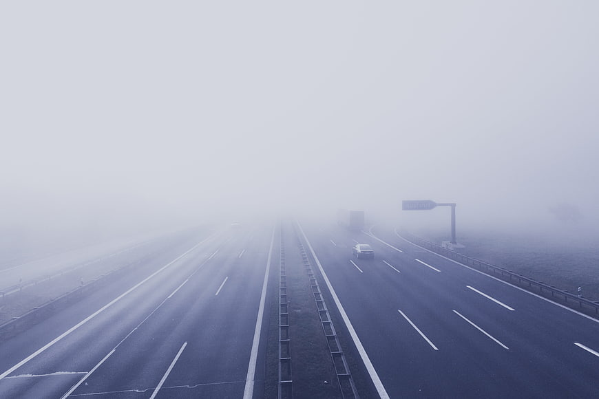 Foggy Highway Road with Cars Driving in Mist