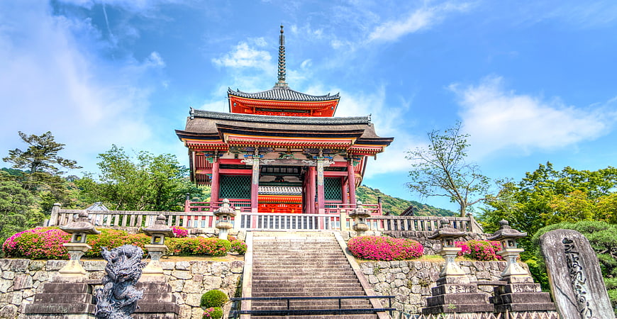 Traditional Japanese Temple Architecture With Vibrant Flowers And Blue Sky