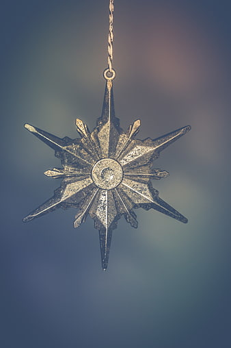 Vintage Silver Star Christmas Ornament Hanging Against Blue Background
