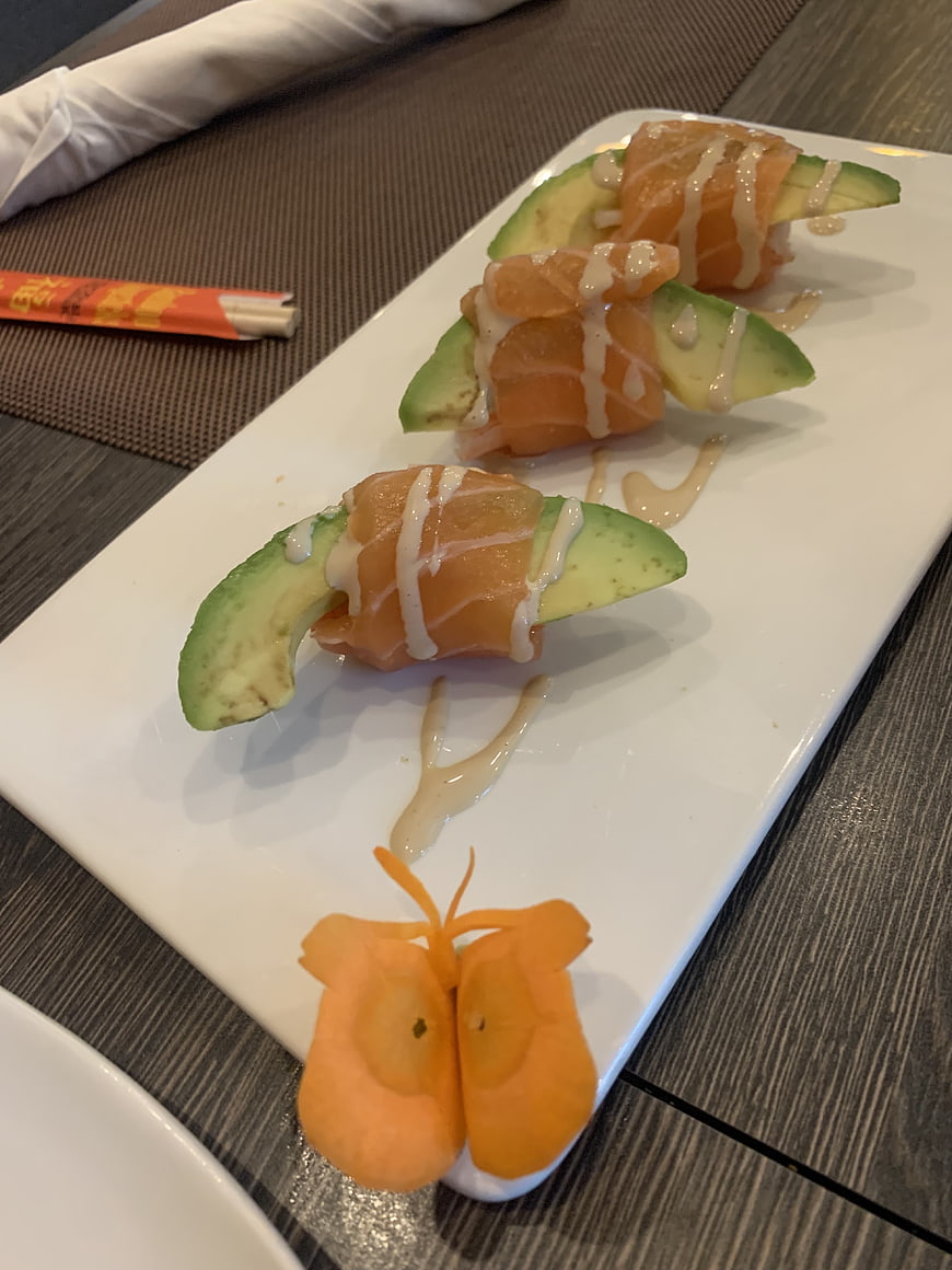 Salmon and avocado sushi rolls with sauce and melon garnish
