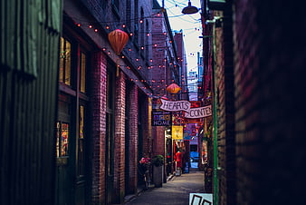 Narrow brick alleyway with hanging lanterns and string lights