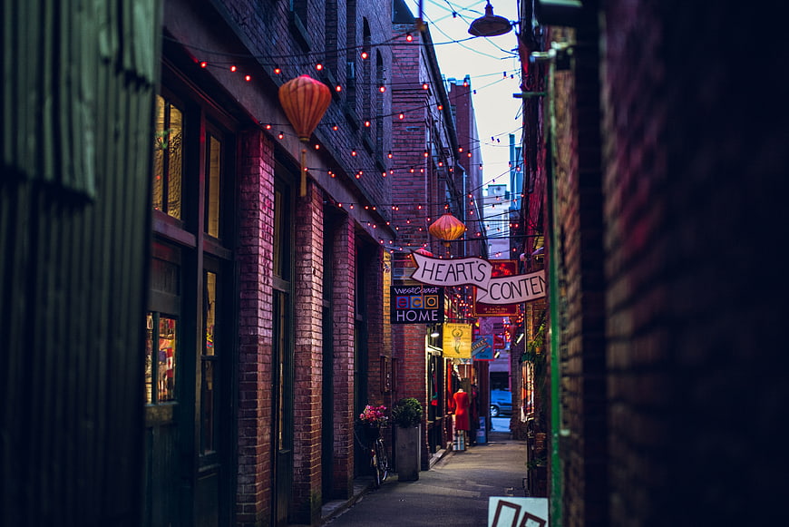 Narrow brick alleyway with hanging lanterns and string lights