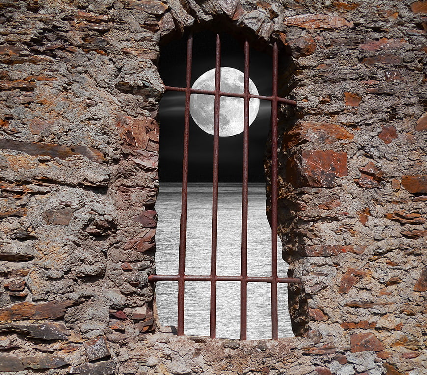 Full Moon Viewed Through Rusty Iron Bars In Stone Wall